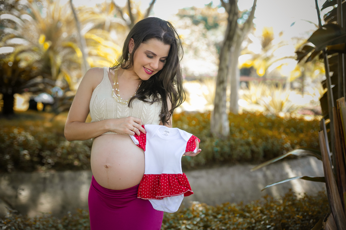 Fotografia de book gestacional com roupinha apoiada  na barriga