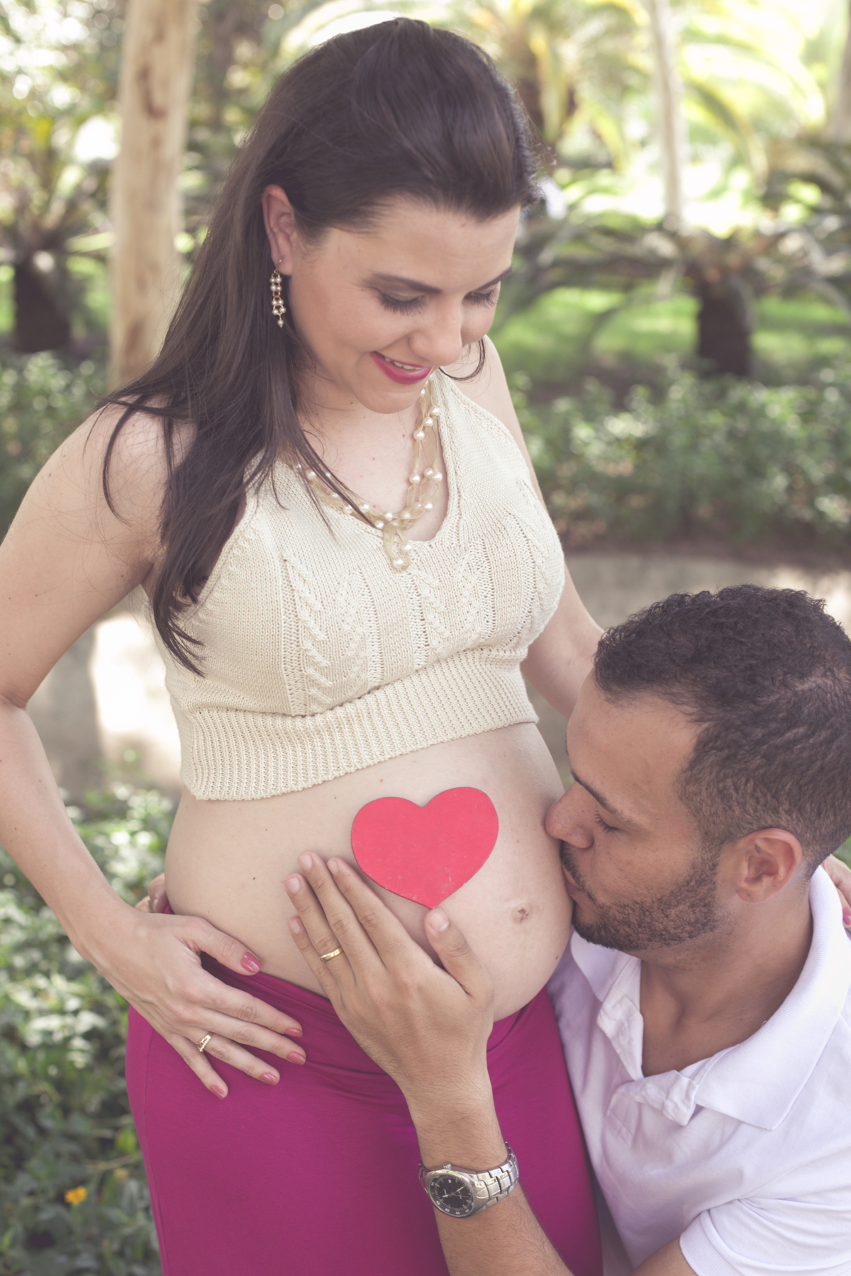 Pai beijando a barriga junto com um coração em ensaio externo