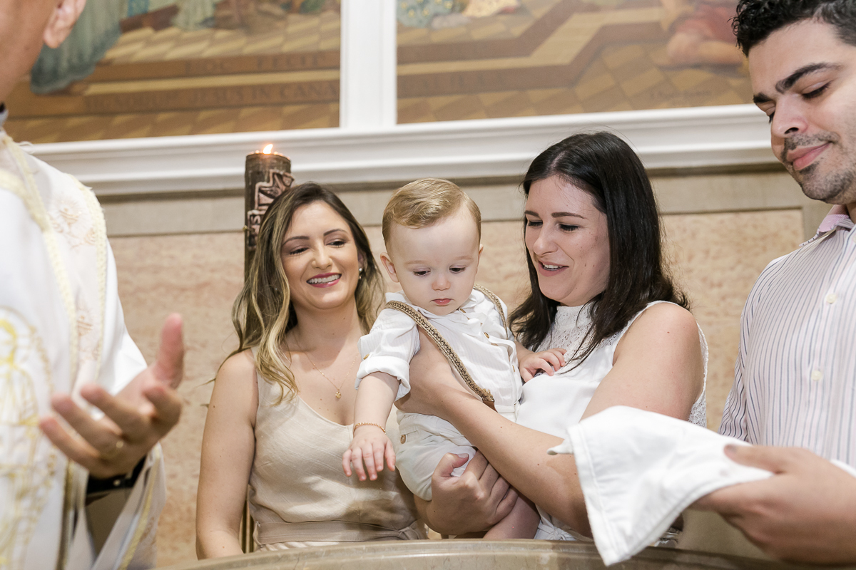 padrinho segurando afilhado na hora do batismo em Paroquia  São 