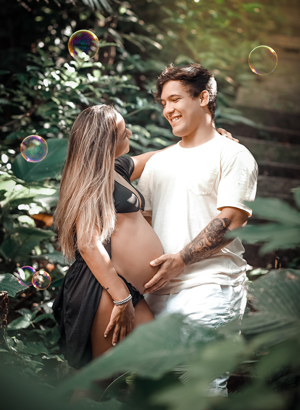 Ensaio romântico de gestante com seu marido segurando sua barriga em Urca