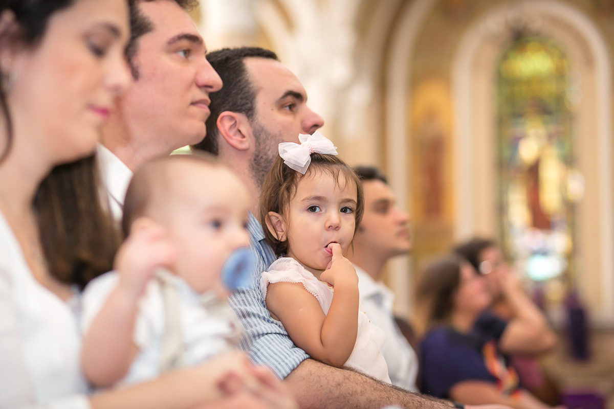 Criança com dedo na boca  em missa de batismo  na Paroquia São Paulo Apostolo