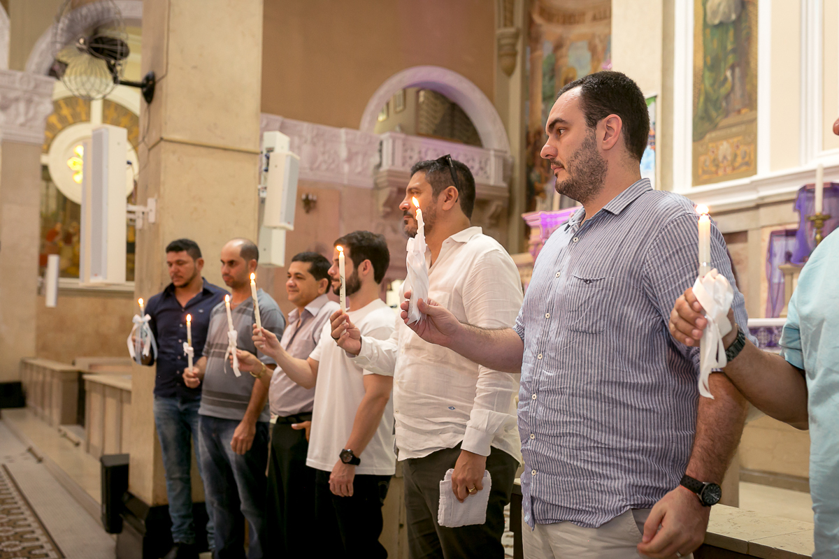 Padrinhos segurando velas na  Paróquia São Paulo Apóstolo em batizado