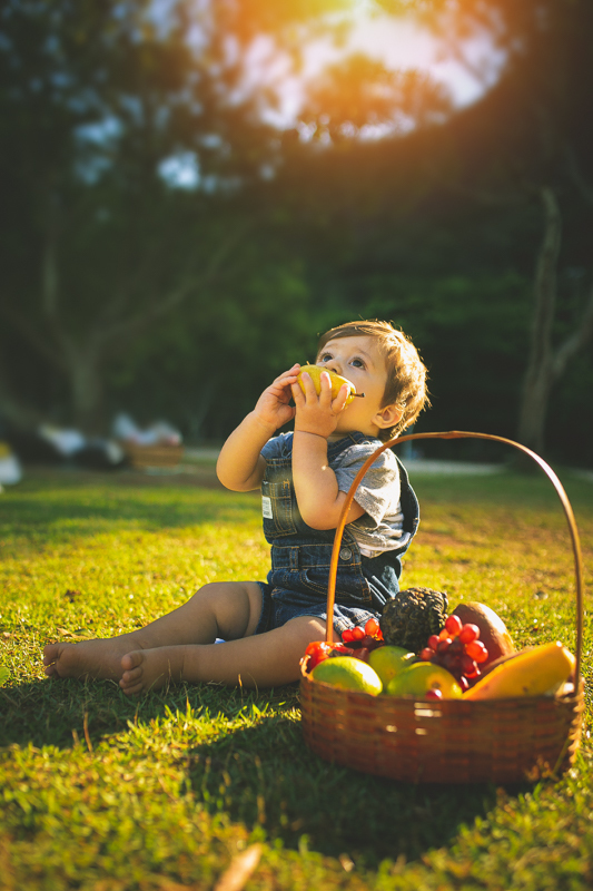 Foto de criança mordendo pera em ensaio infantil externo