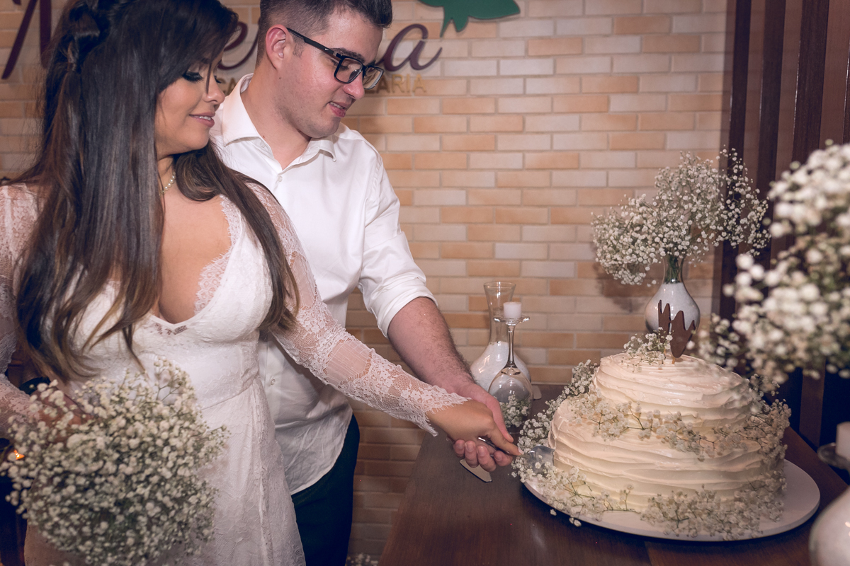 Noivo cortando bolo em jantar de casamento