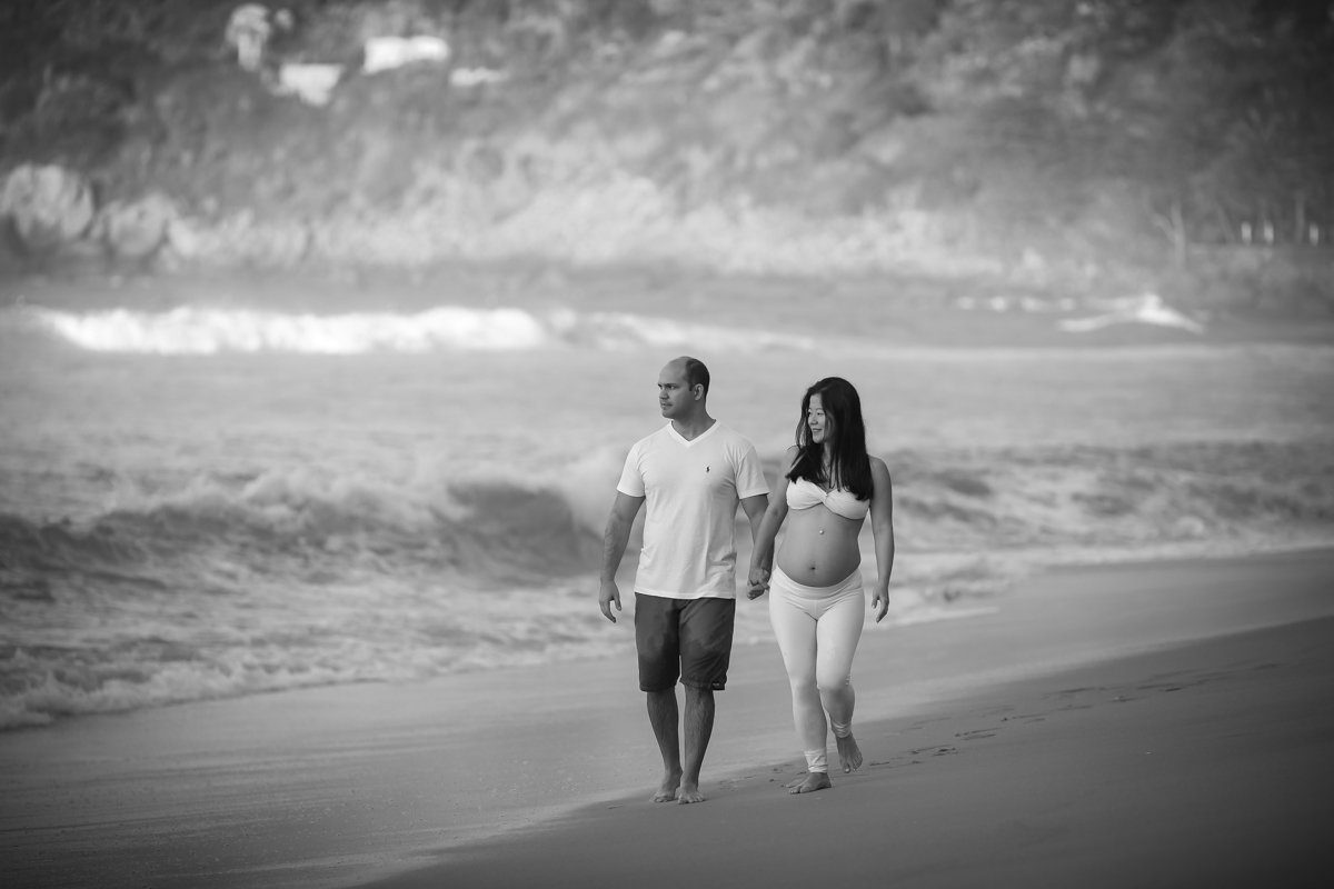 Gestante em ensaio na praia de grumari caminhando junto com esposo de mãos dadas