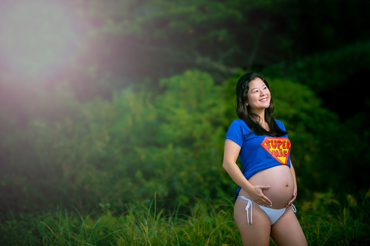 Gestante colocando mão na barriga e ao fundo verde da natureza em Grumari-Rj