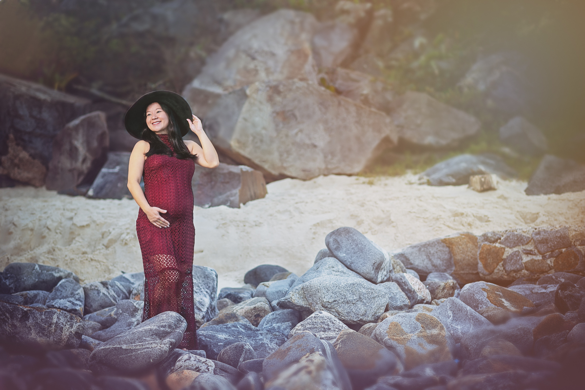Ensaio gestante na praia em cima das pedras com vestido longo vinho-Grumari-RJ