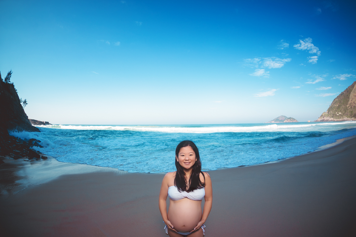 Gestante segurando a barriga em ensaio ao fundo mar-Grumari

