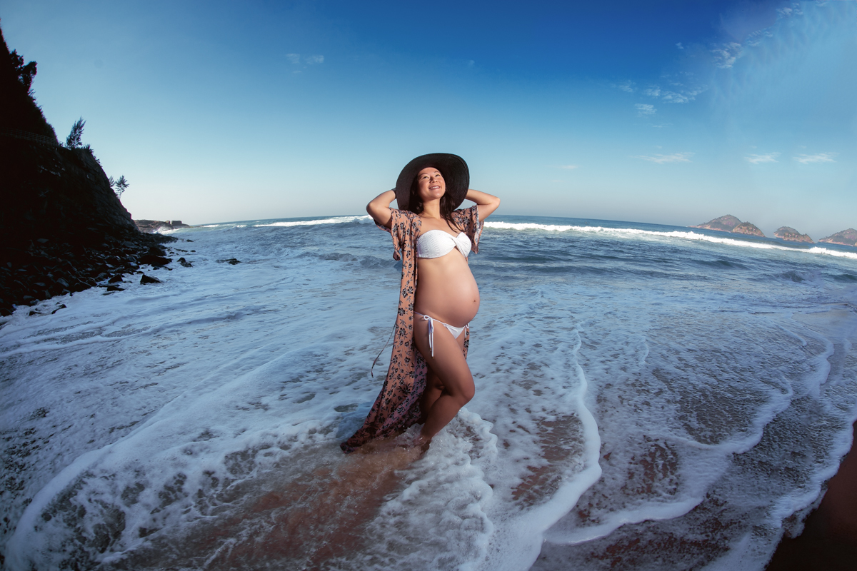 Gestante em ensaio externo com chapéu preto em praia Grumari-RJ