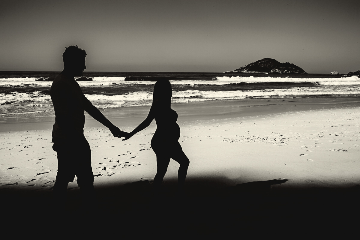Casal andando em ensaio fotográfico externo gestacional na Prainha/RJ