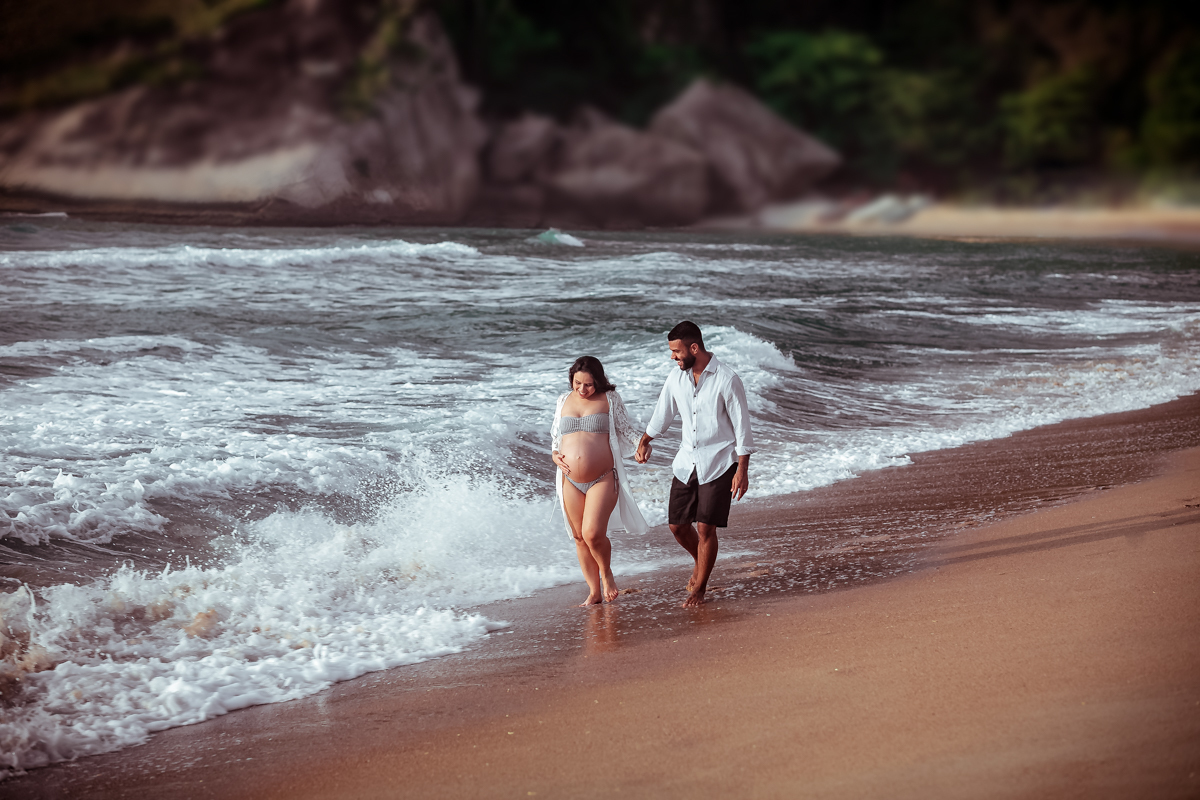 Casal andando na praia em ensaio gestante/Grumari
