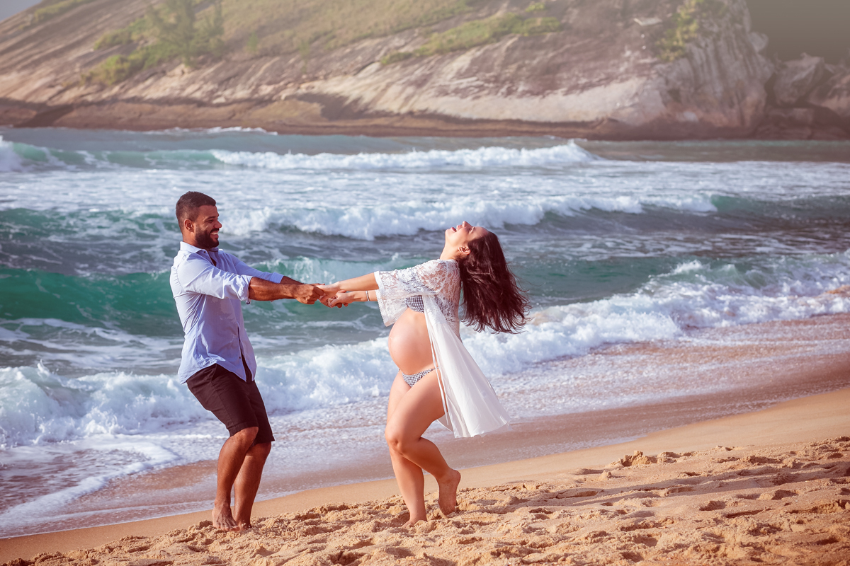 Casal brincando na areia em ensaio fotográfico de gestante externona praia/RJ