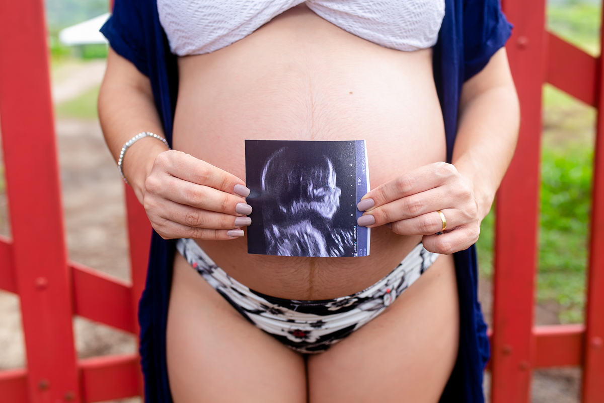 Ensaio de gestante com foto de ultra em cima da barriga em Grumari/RJ