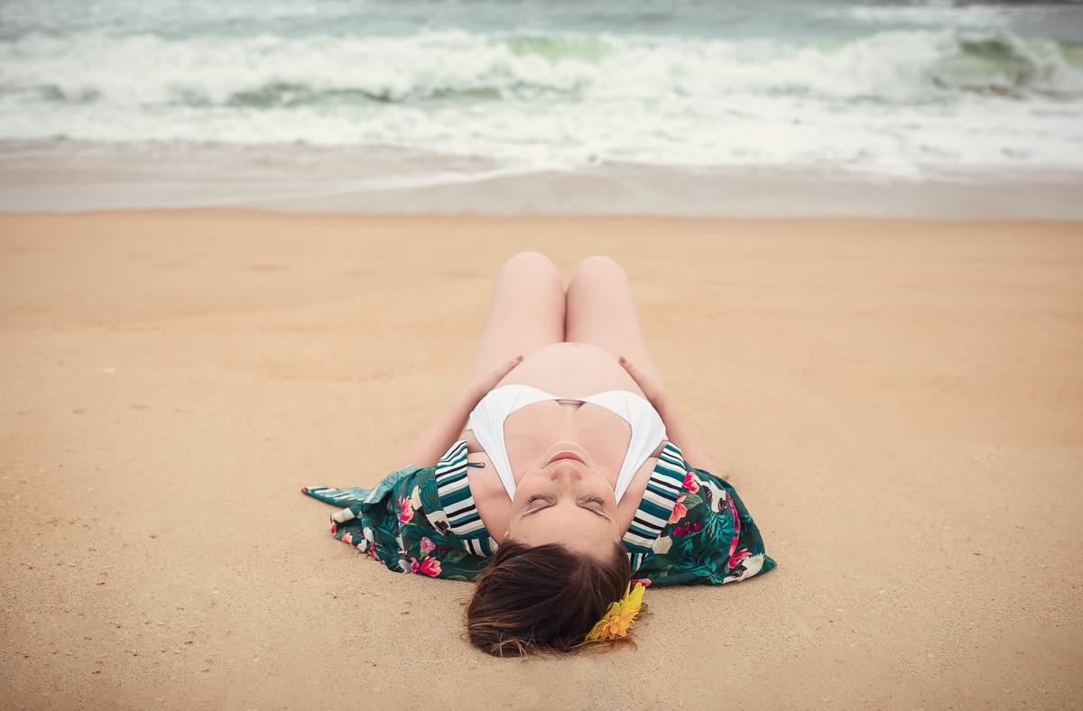Gestante deitada na areia em ensaio fotográfico na praia de Grumari/RJ