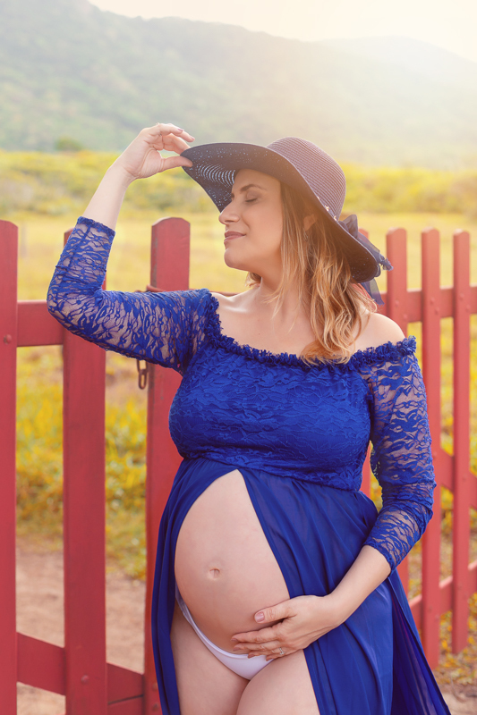 Ensaio de gestante em Grumari  gestante fazendo pose em frente portão vermelho