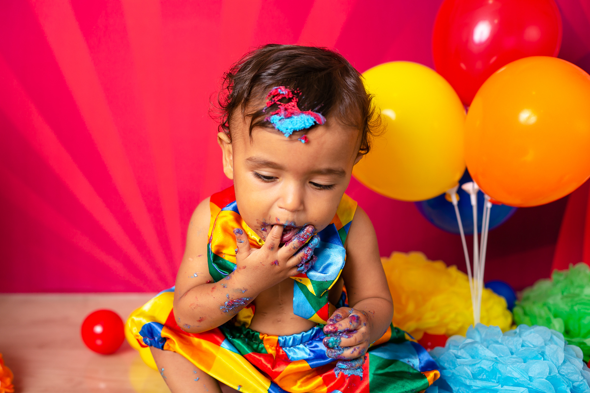 Smash de cake menino lambendo os dedos em seu ensaio fotográfico em estúdio tema circo