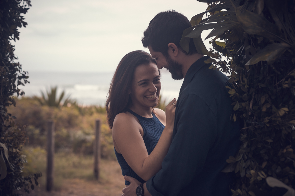 Ensaio de casal em Grumari eles encostados no portal/RJ