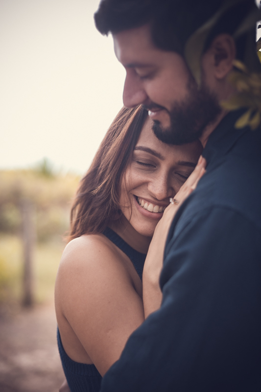 Noiva sorrindo enquanto seu noivo a abraça em ensaio fotográfico pré-casamento/RJ