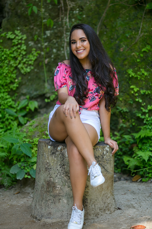 Gestante em seu ensaio externo sentada em um troco