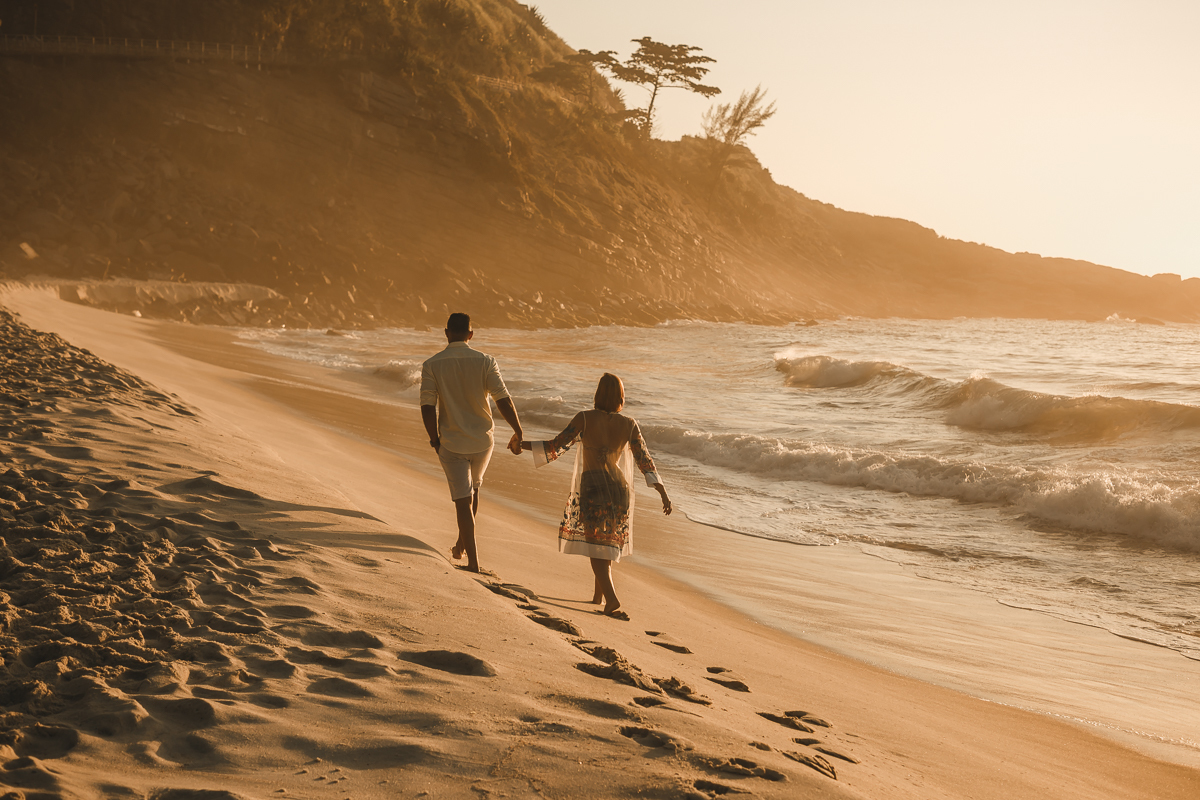 casal caminhando em praia ao nascer do sol em seu ensaio /na prainha/Rj
