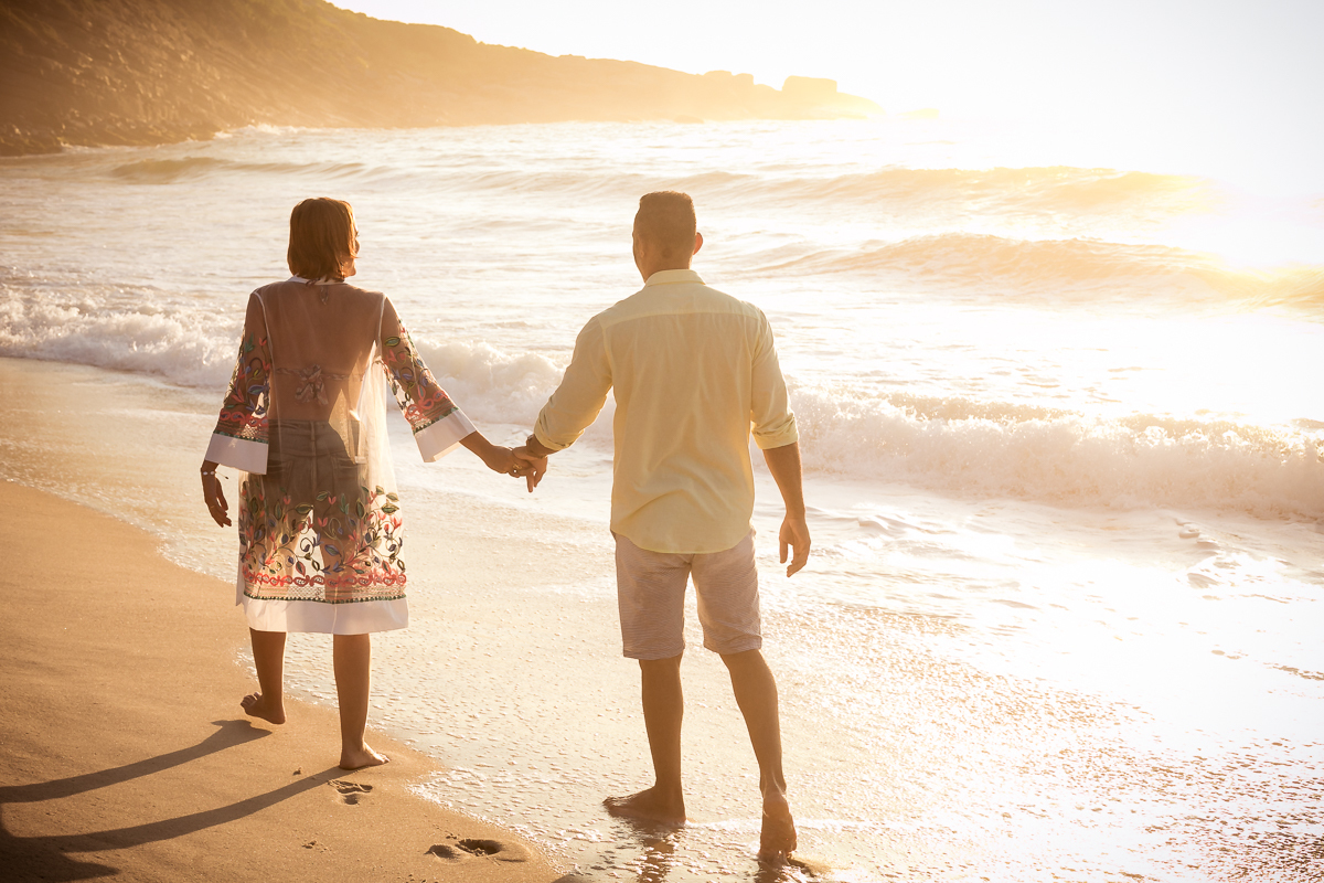 Casal andando de mãos dadas em seu ensaio fotográfico na praia d prainha/RJ