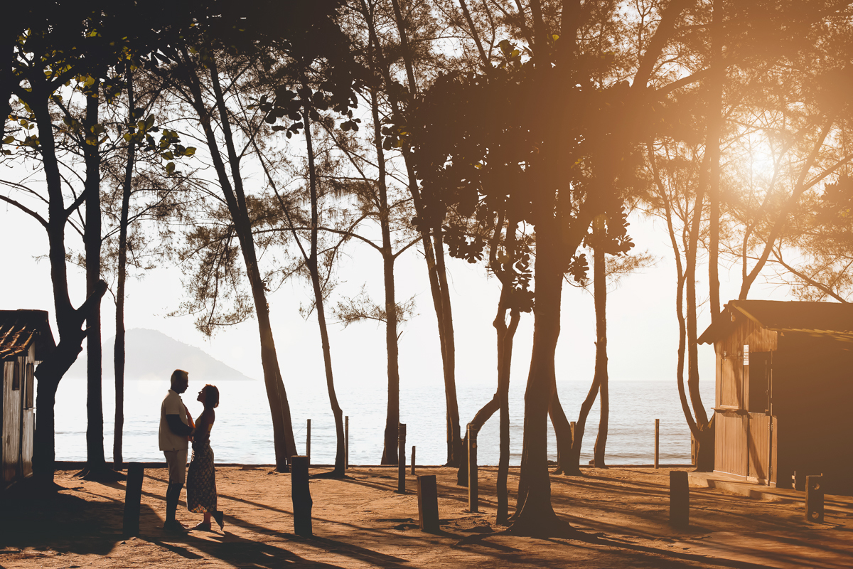 Casal entre árvores ao fundo mar ao entardecer em grumari
