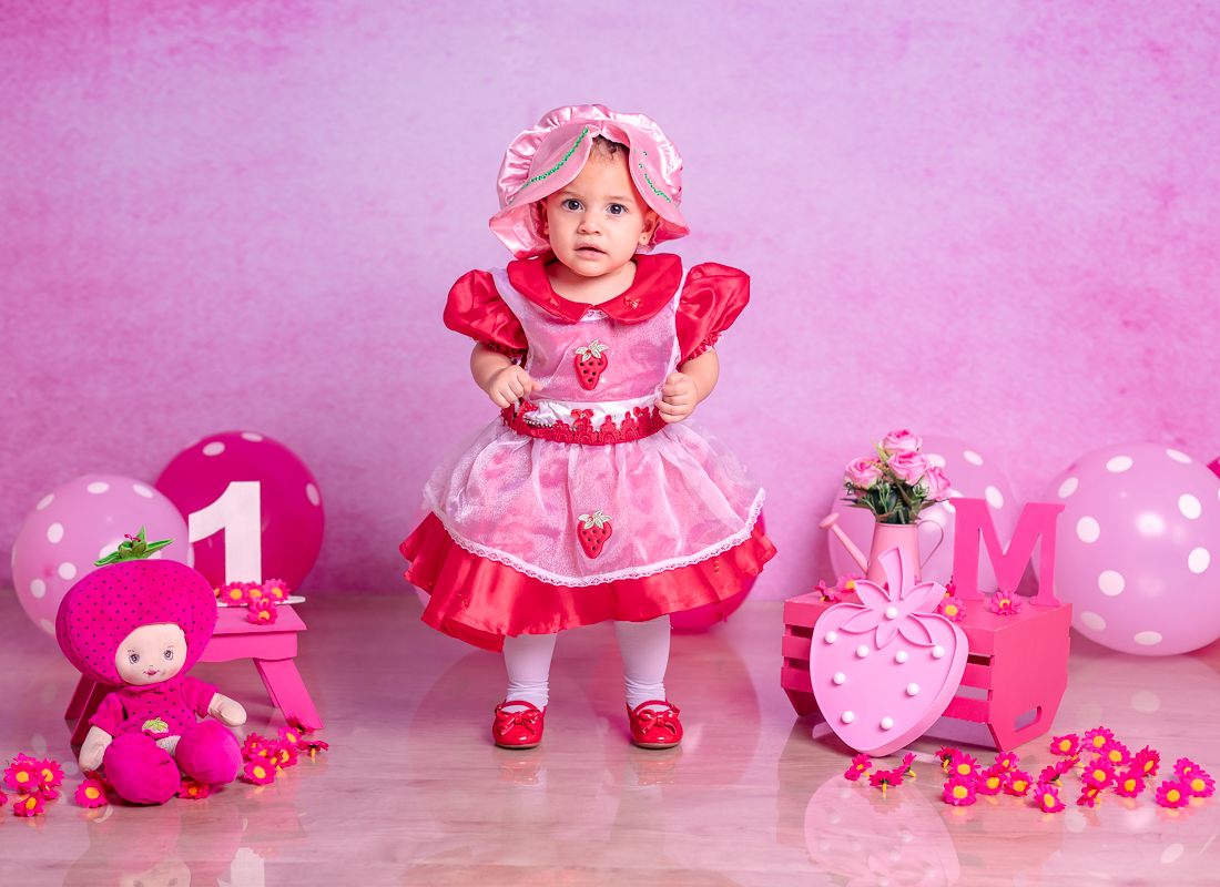 Manuella em sua fantasia de moranguinho em ensaio temático em ensaio em estúdio pré-aniversário de 1 ano