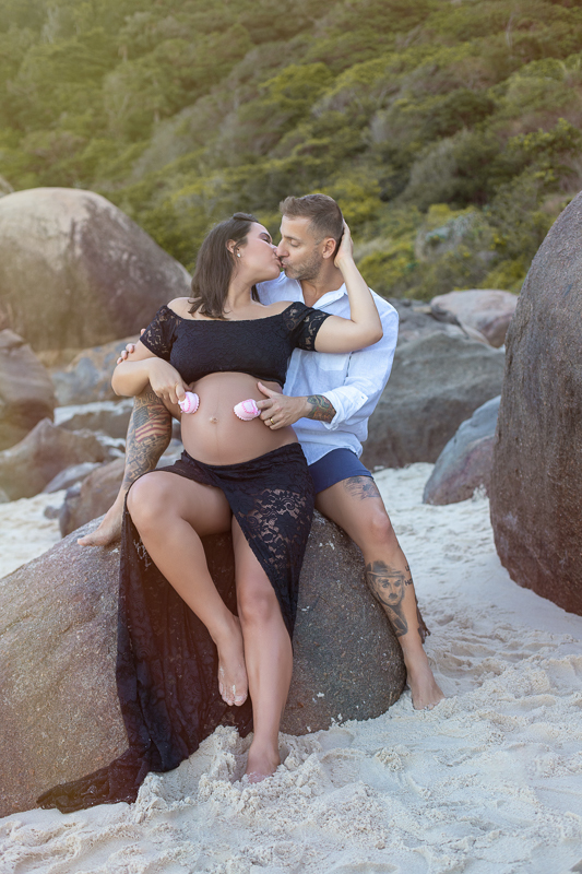 Ensaio de fotos de gestante junto com seu esposo sentada em pedra-prainha-RJ