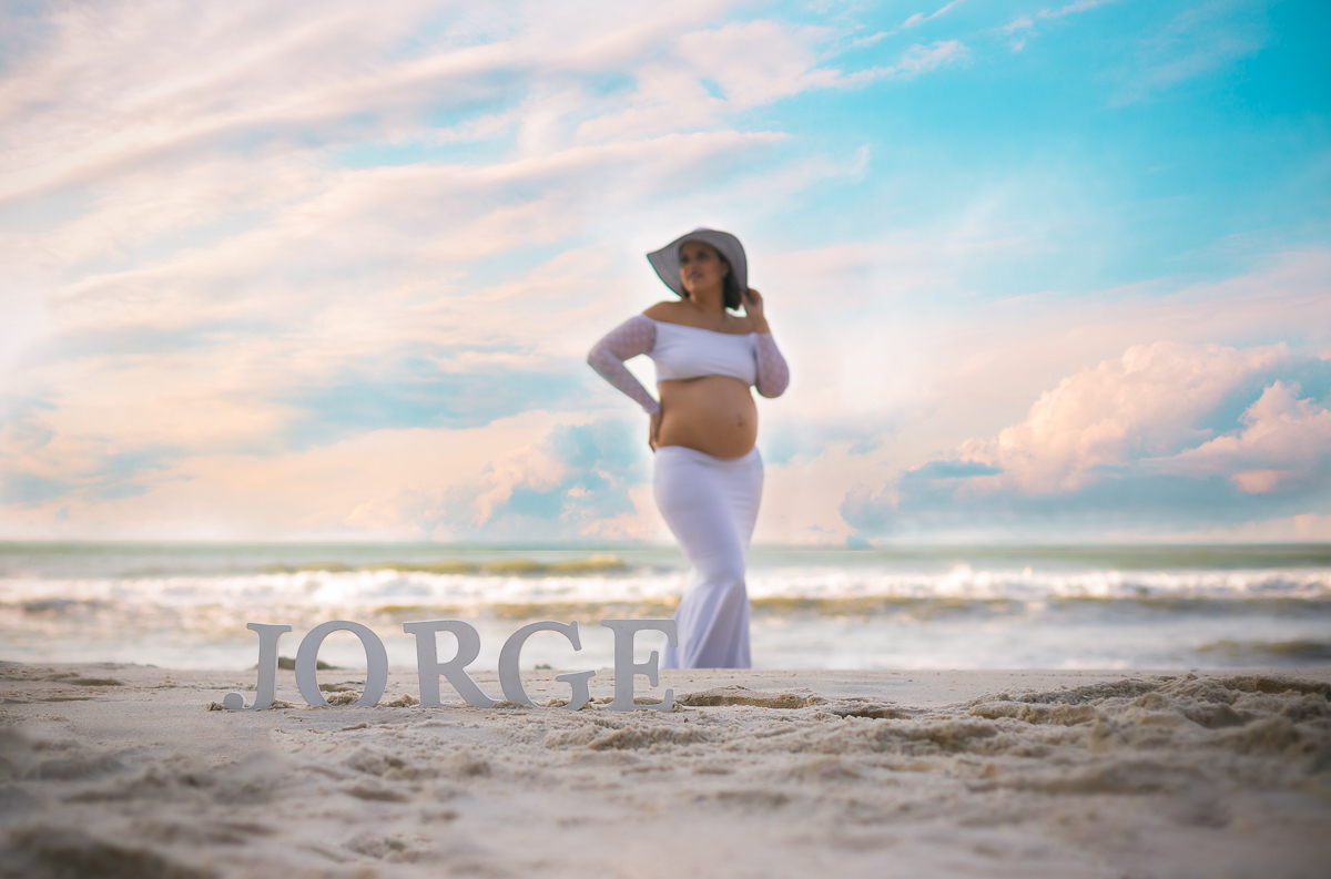 nome do bebê na areia ao fundo gestante em seu ensaio externo na prainha-RJ