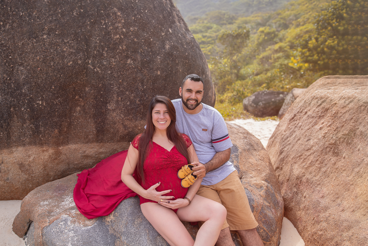 gestante sentada em pedra junto com esposo-ensaio de gestante externo-rj