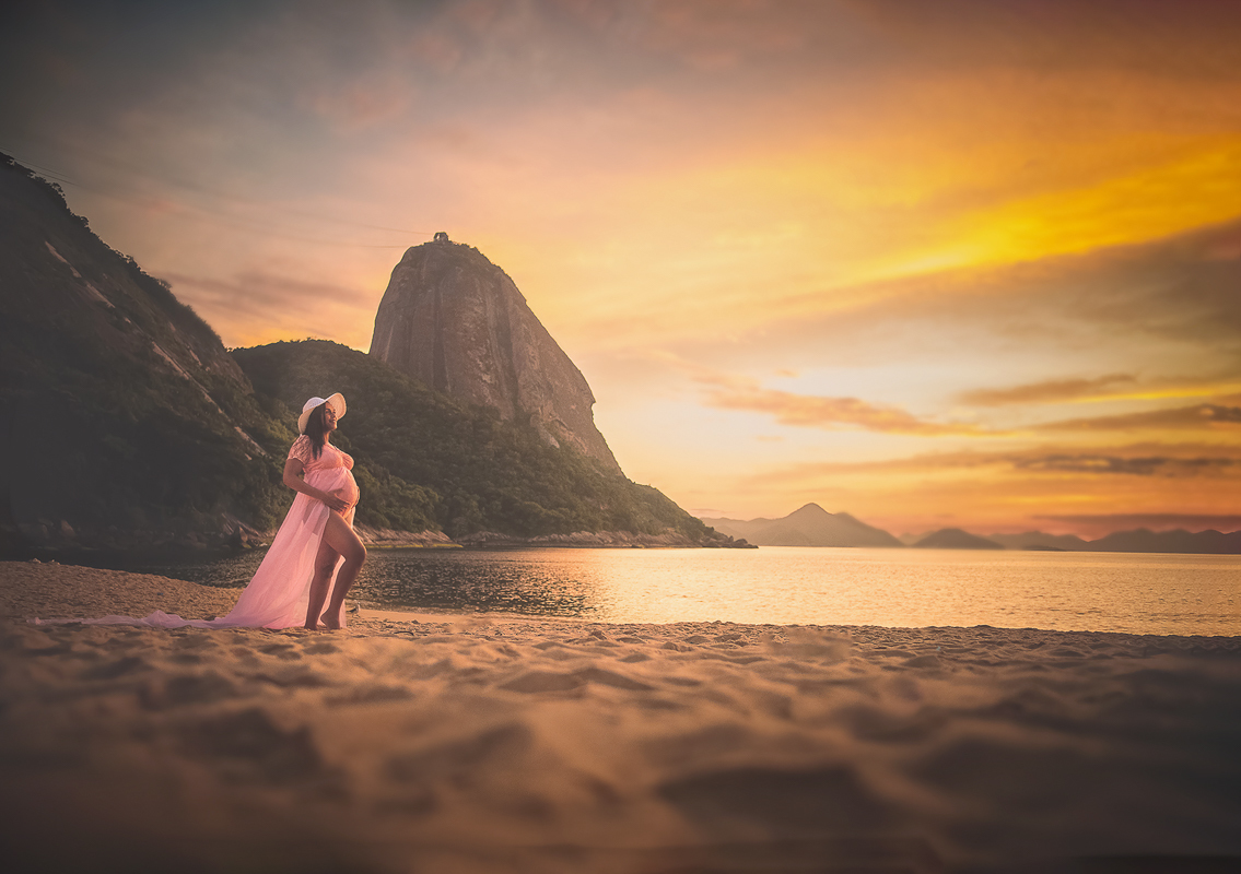gestante em ensaio fotográfico na praia vermelha ao fundo