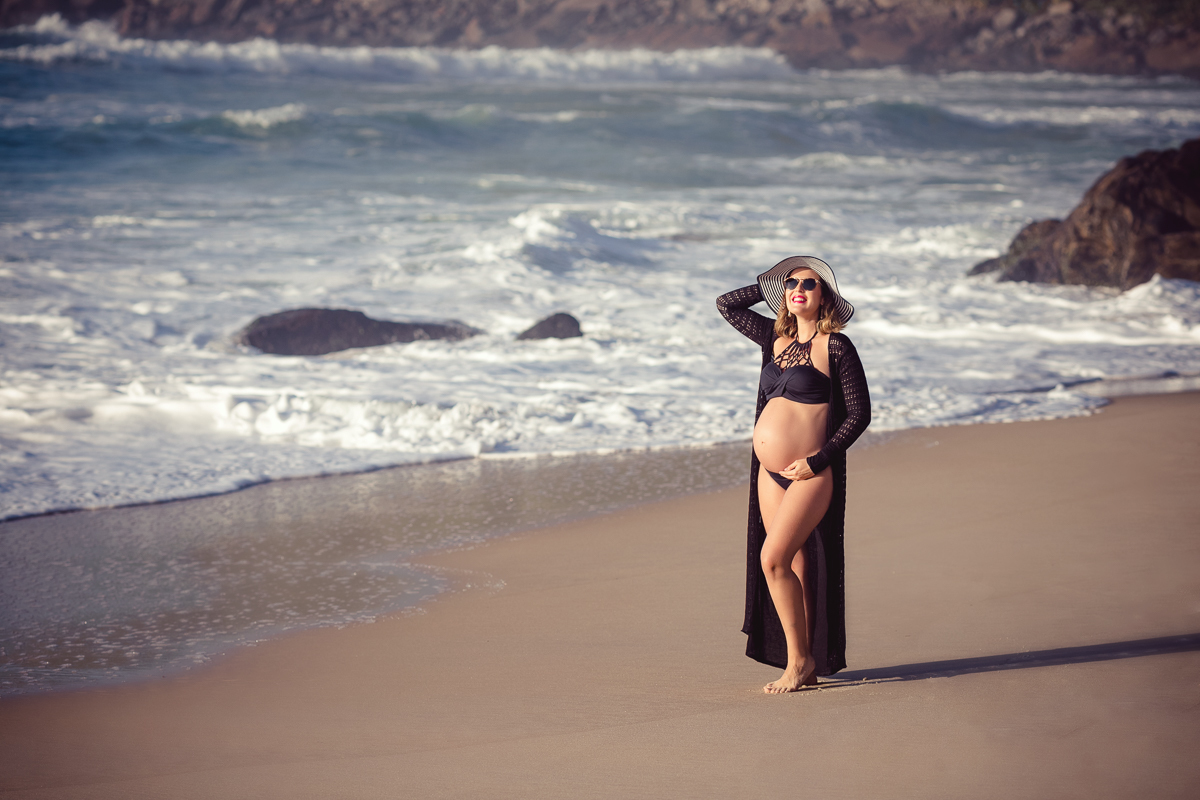 gestante posando com a mão na barriga em ensaio externo-prainha RJ