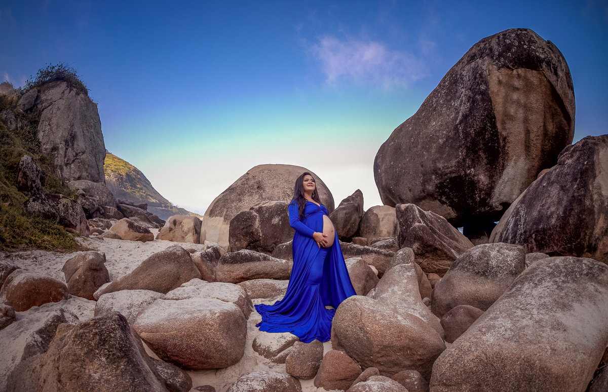 gestante em cima de pedras ao fundo céu azul em ensaio fotográfico-prainha-rj