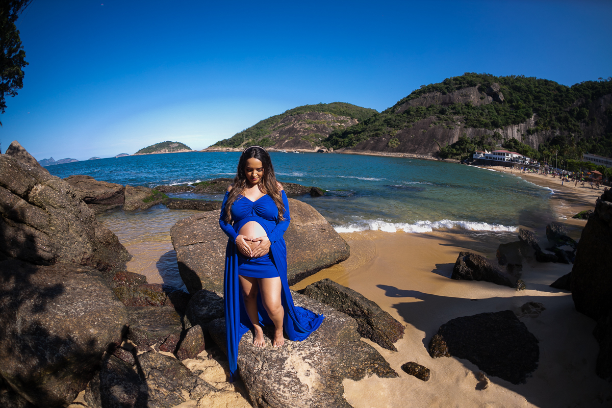 gestante  posando em cima da pedra olhando para barriga em ensaio fotografico-praia da urca-praia vermelha -RJ