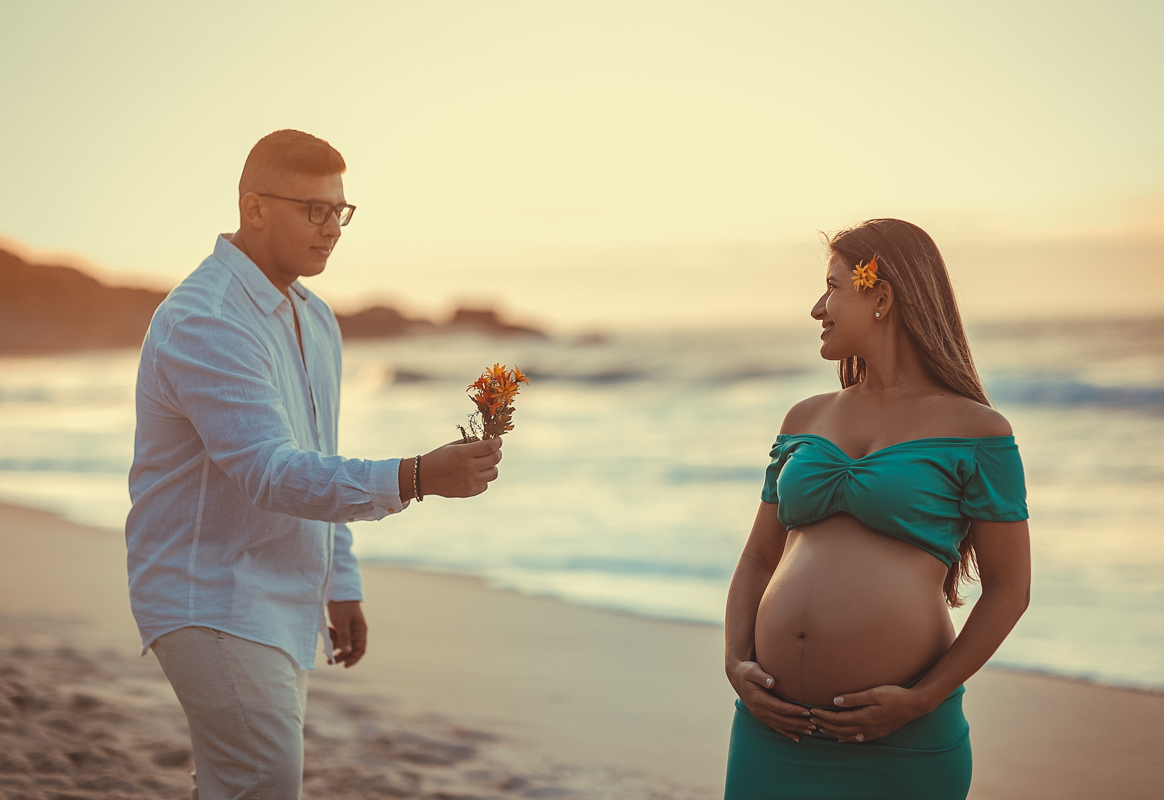 ensaio romântico de gestante esposa oferece flor e faz pose-praia-ensaios-book-gestante