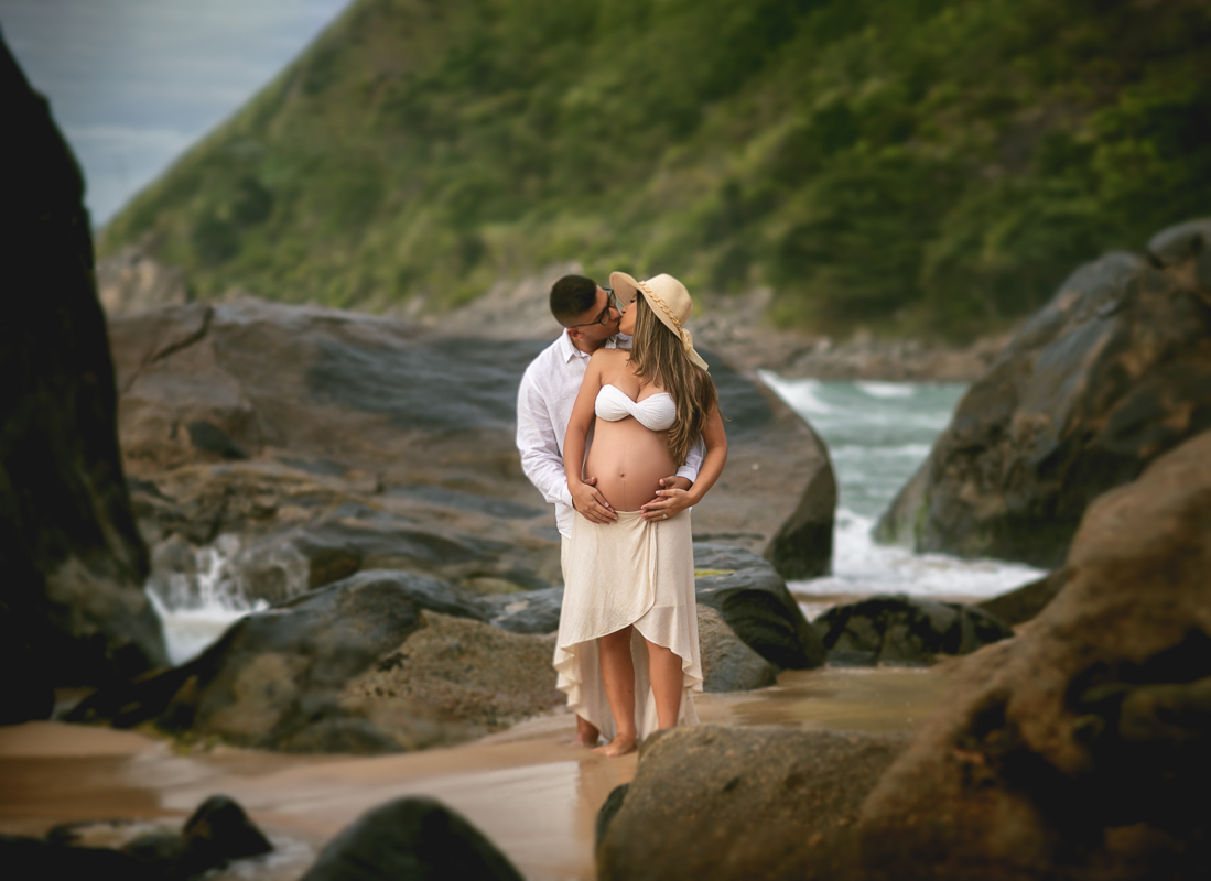 esposo dando um beijo e segurando a barriga da gestante-ensaio externo na praia