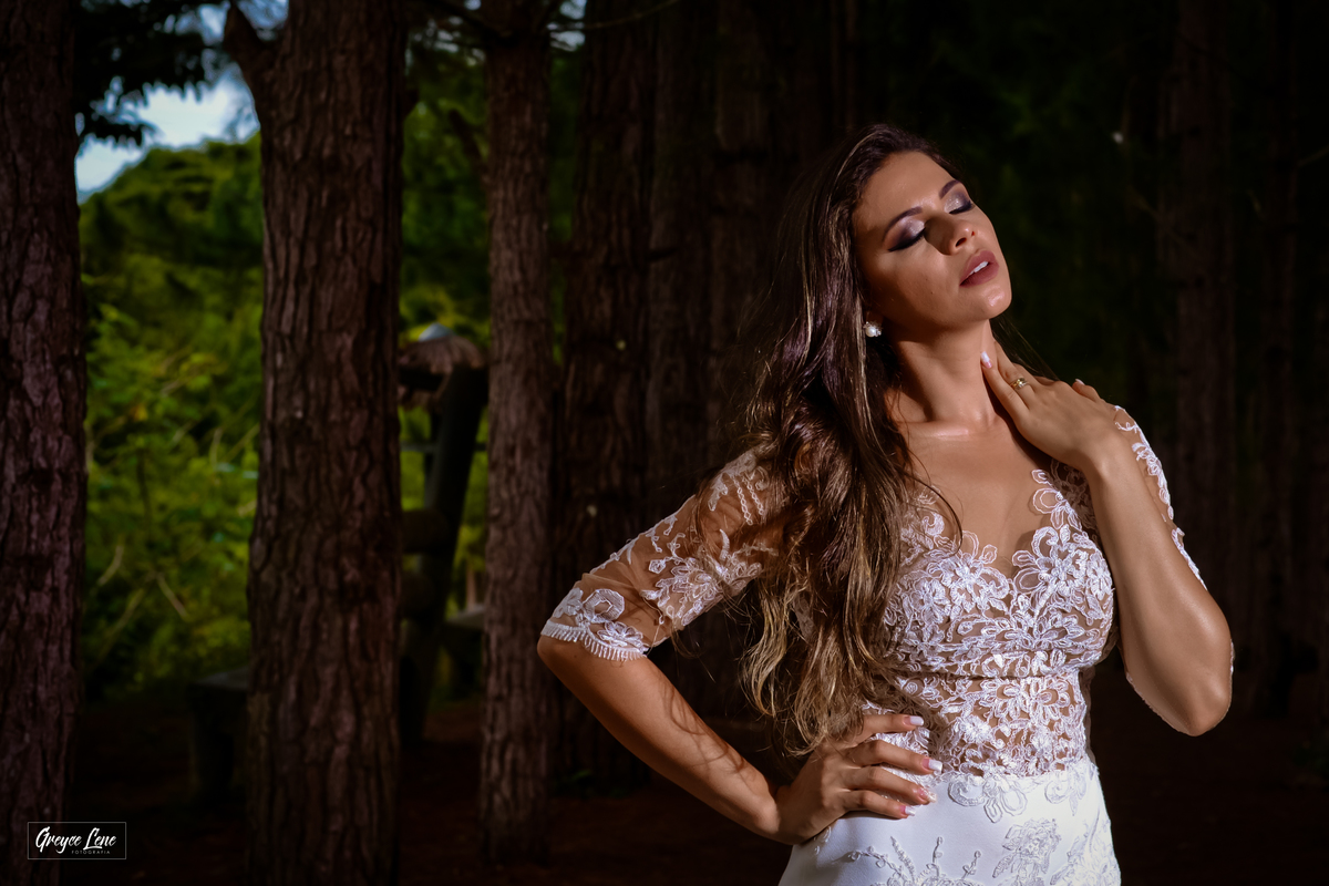 noiva de olhos fechados acariciando o pescoço com o rosto levantado para cima em meio as arvores sessão externa em porto velho ro