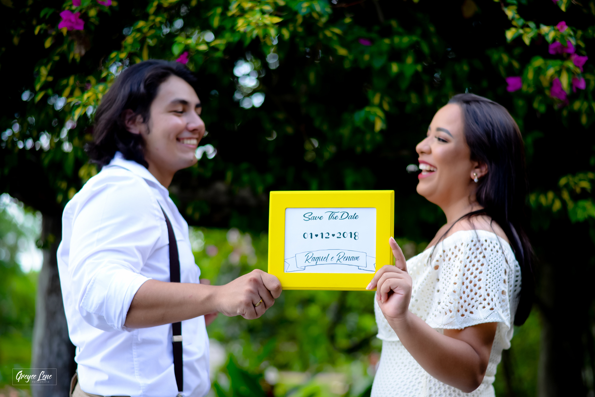 casal sorrindo onlhando um para o outro segurando a placa de save the date ensaio casal pre casamento porto velho