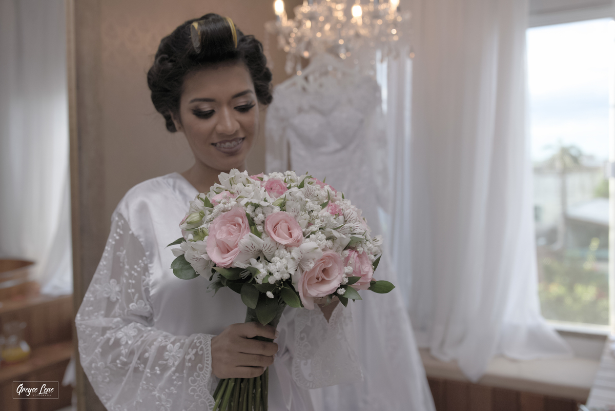 noiva segurando o buque com vestido pendurado ao fundo