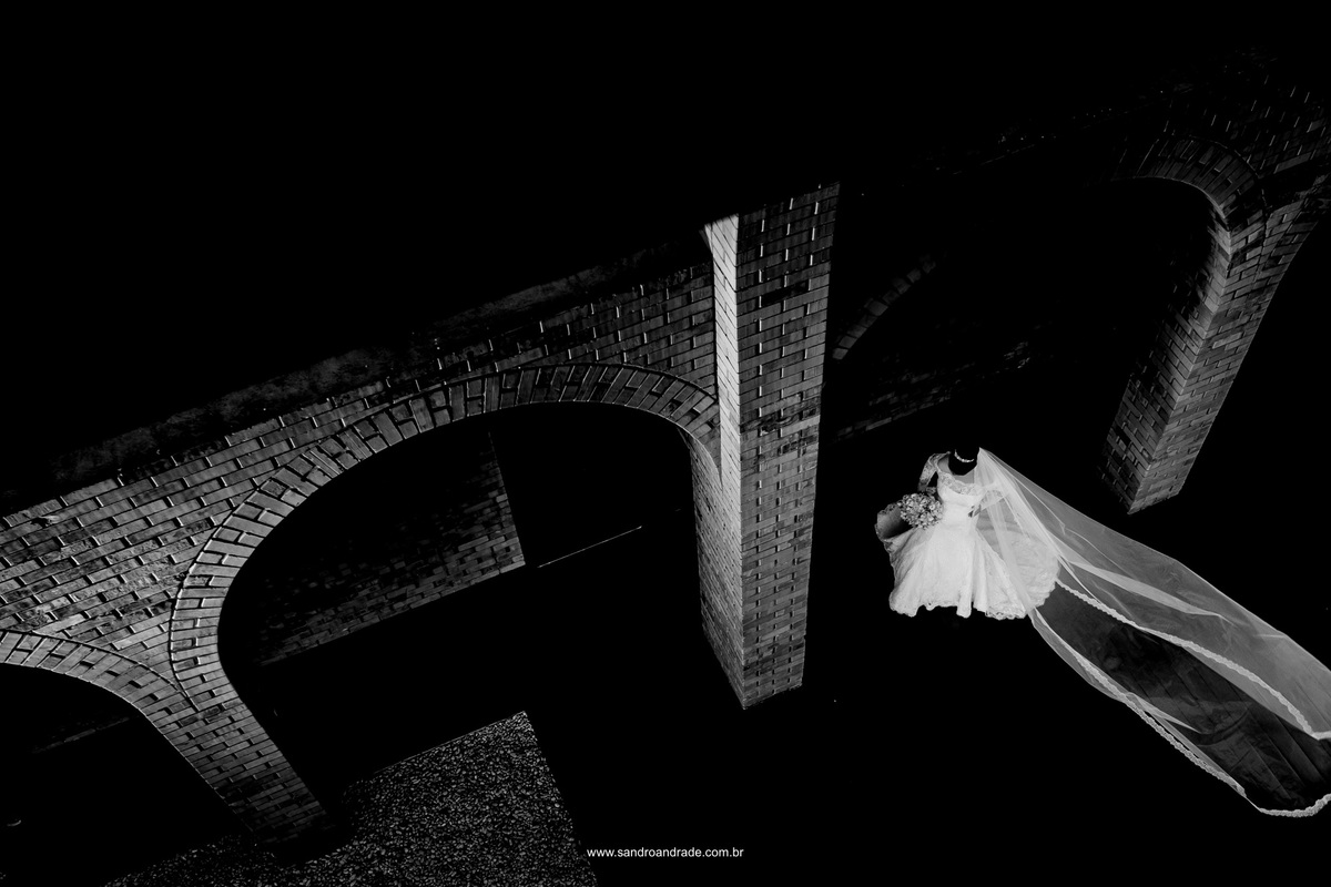 Um click belíssimo em preto e branco pegando os arcos da mansão e a noiva bem singela ao fundo.