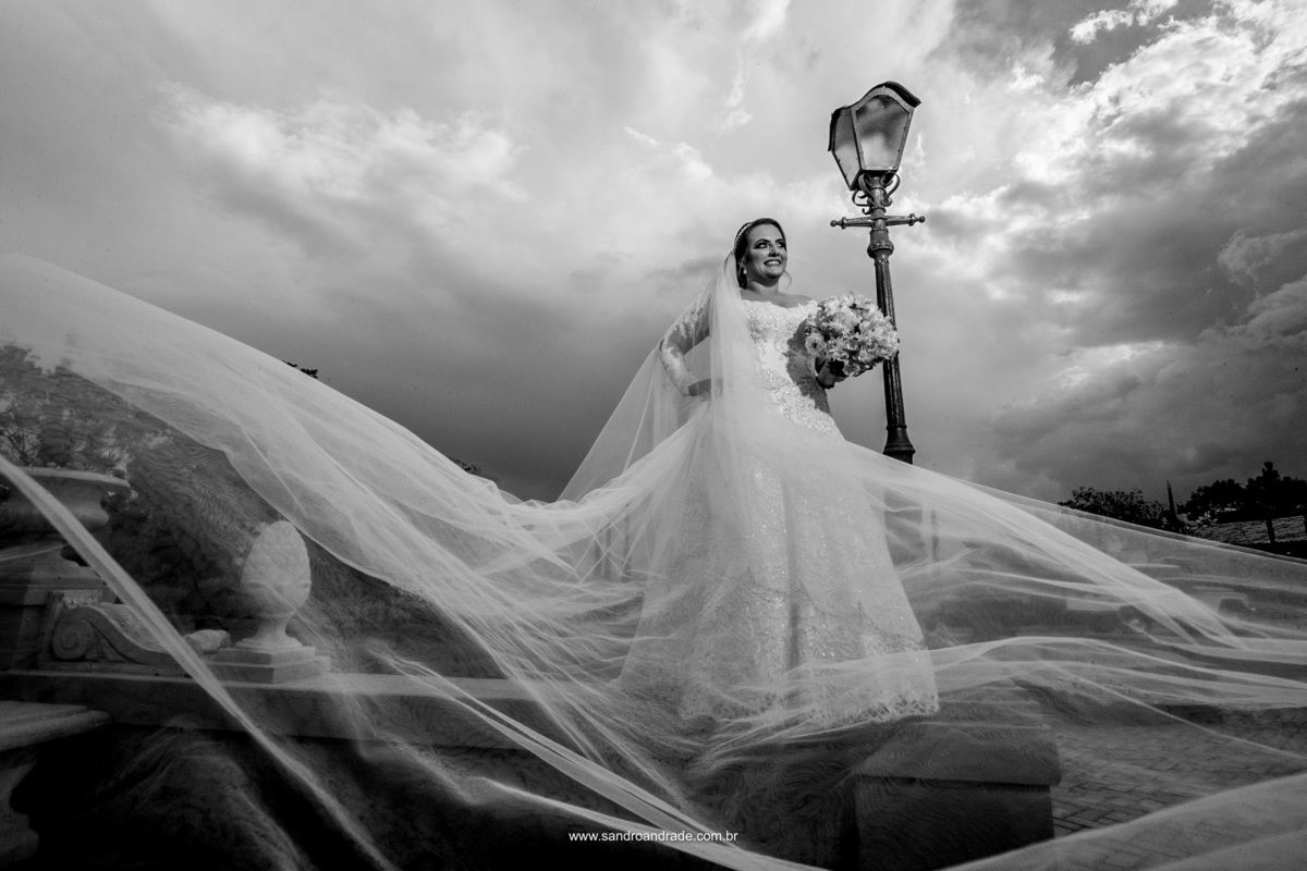 Céu com nuvens carregadas, uma chuva preste a descer e ela linda em seu vestido de noiva, em uma fotografia em preto e branco, perfeita.
