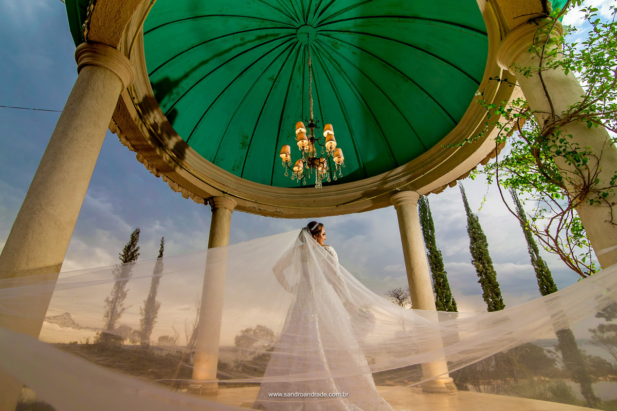 Um lindo gazebo a beira do lago, em meio ao jardim e a noiva está deslumbrante.