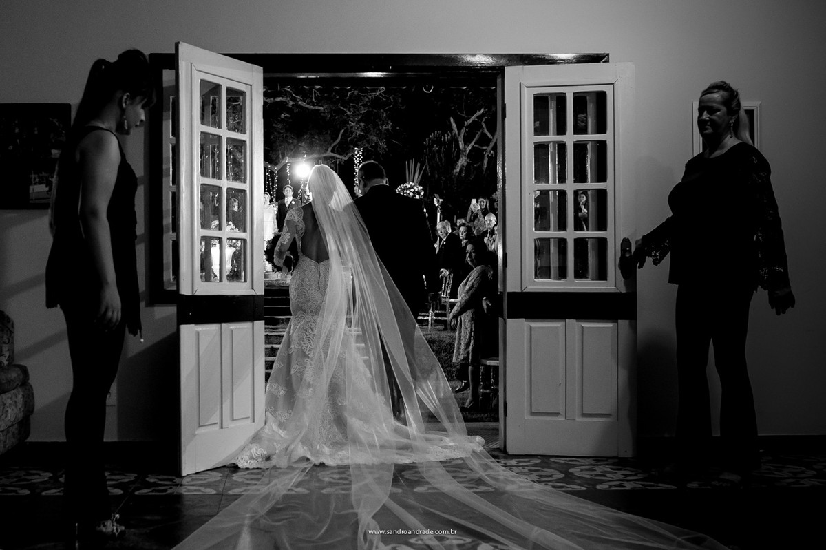 Momento imperdivel, feito pelo fotografo Sandro Andrade na entrada da noiva com seu pai e o noivo ao fundo vendo sua noiva linda, em um belíssimo vestido de noiva.