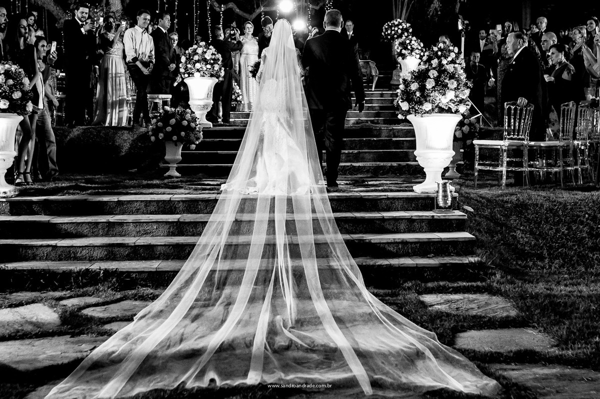 Noivo emocionado ao fundo, vendo sua linda noiva entrando ao lado de seu pai.