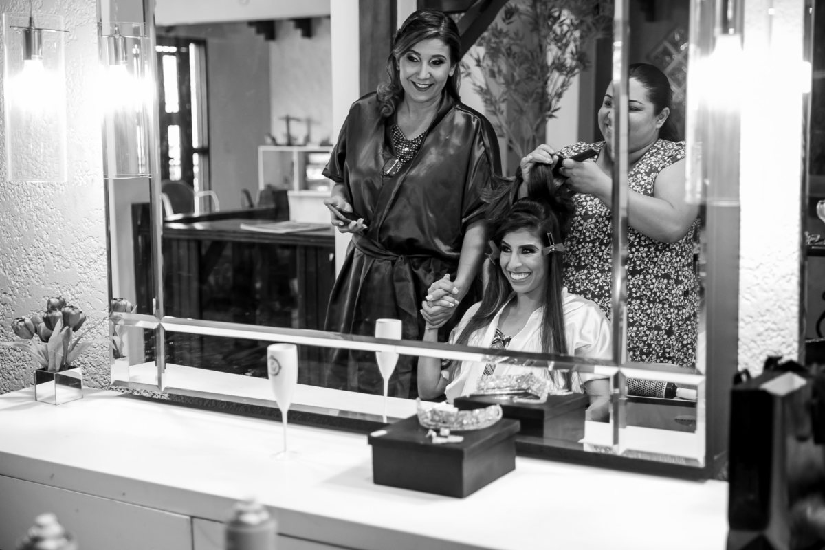 Preparando seu penteado, uma madrinha se aproxima da noiva para dar um apoio e perguntar sobre o friozinho na barriga. 