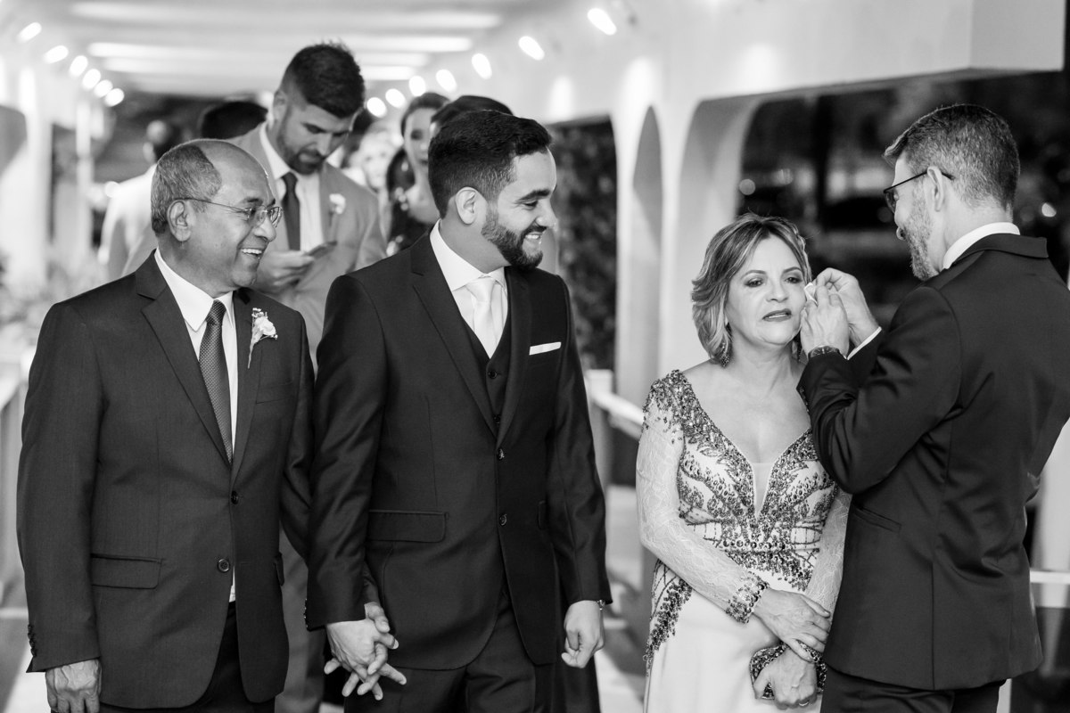 Nos corredores da Paróquia Militar do Oratório do Soldado e já com a fila do cortejo feita a mãe do noivo se emociona e o Christian de Brito carinhosamente seca as lagrimas dela, cuidado para não borrar a maquiagem. 