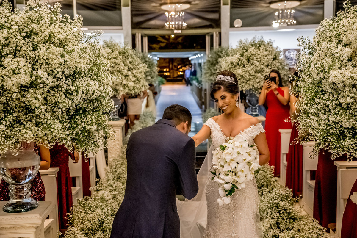 Como um cavaleiro ele recebe sua amada, um beijo em sua mão e ela sorri feliz e encantada com o cavalheirismo de seu amado noivo.