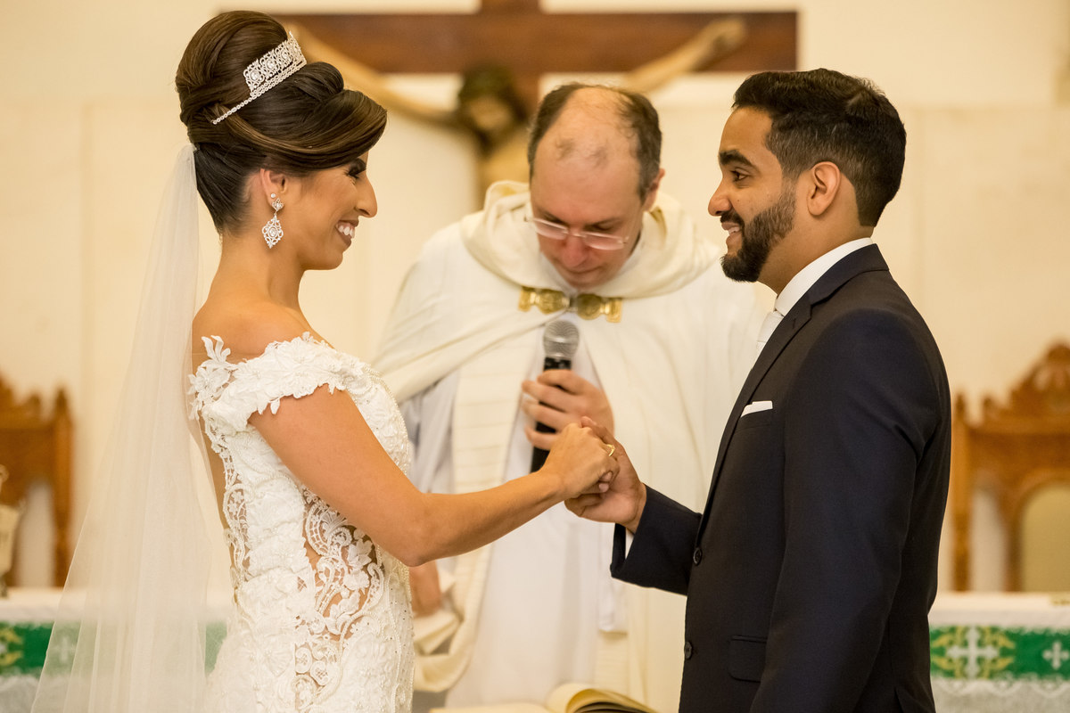 O casal de frente um para o outro no momento dos votos, felizes e apaixonados.