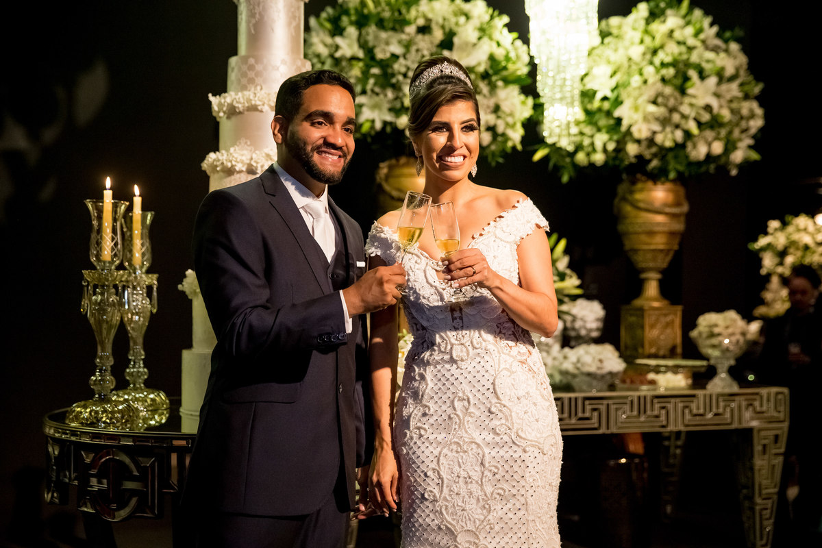 O casal se vira para seus convidados e todos brindam juntos.