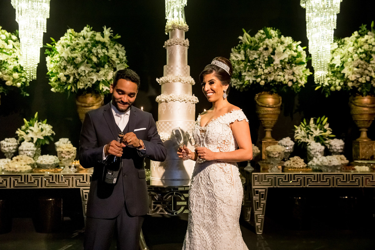 Chegando ao Maastik, casa de eventos em Brasilia os noivos se direcionam até a mesa do bolo para o momentos das fotos e do brinde. O noivo abrindo o champagne.